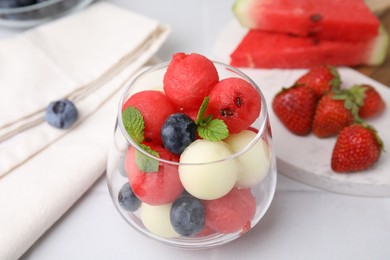 Tasty watermelon and melon balls with blueberries in glass on white table, closeup