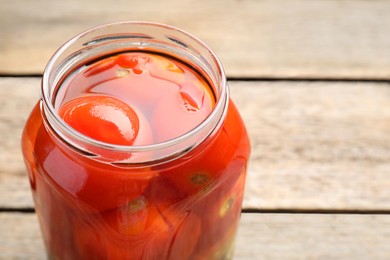 Photo of Tasty pickled tomatoes in jar on wooden table, closeup. Space for text