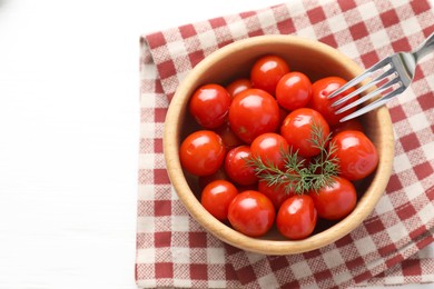 Tasty pickled tomatoes in bowl, dill and fork on white table, top view. Space for text