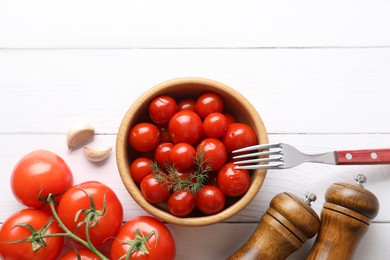 Photo of Tasty pickled tomatoes in bowl, fresh vegetables, dill, garlic and fork on white wooden table, top view