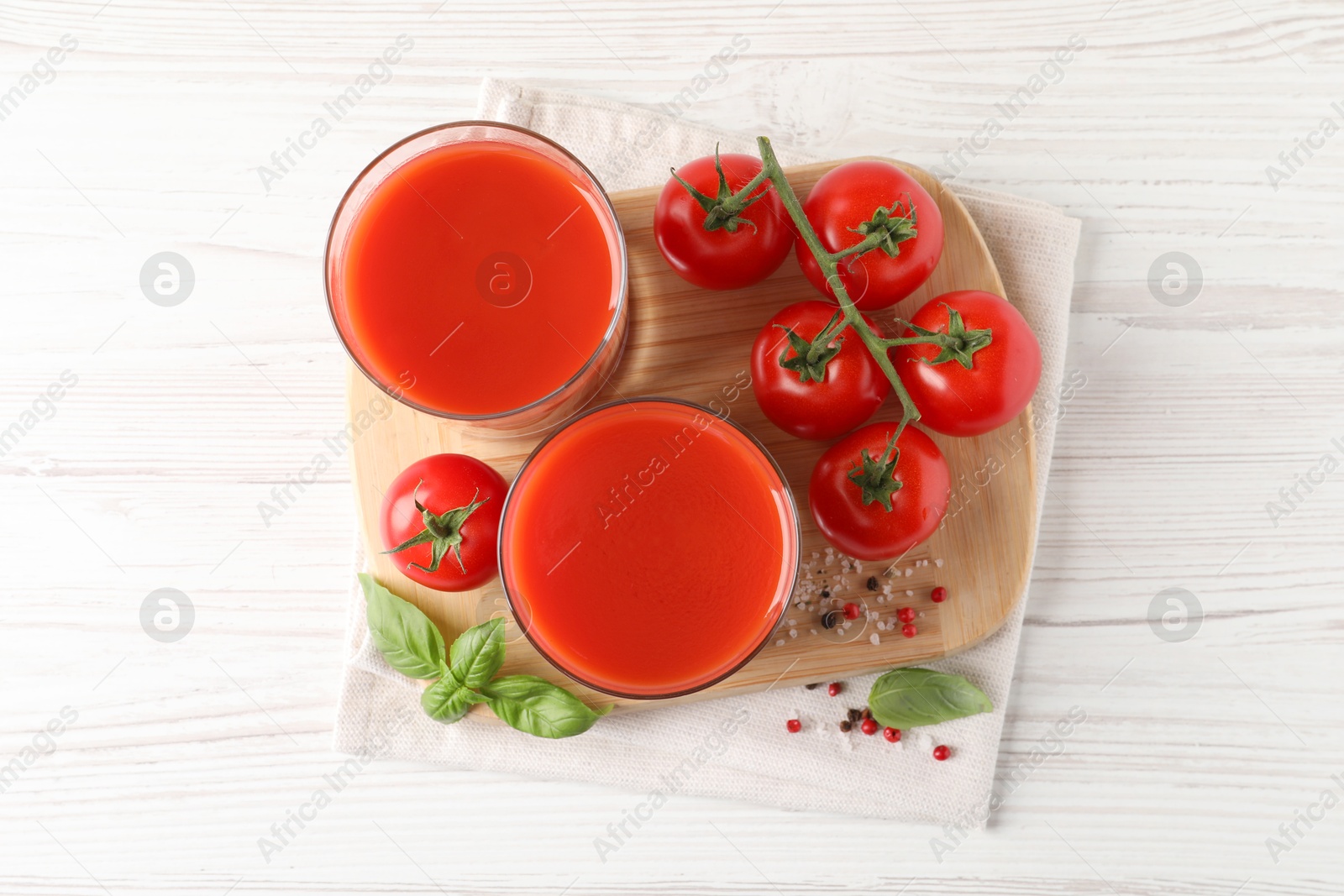 Photo of Tasty tomato juice in glasses with fresh vegetables and spices on white wooden table, flat lay