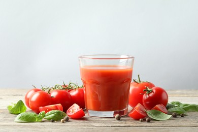 Photo of Tasty tomato juice in glass with fresh vegetables and spices on wooden table