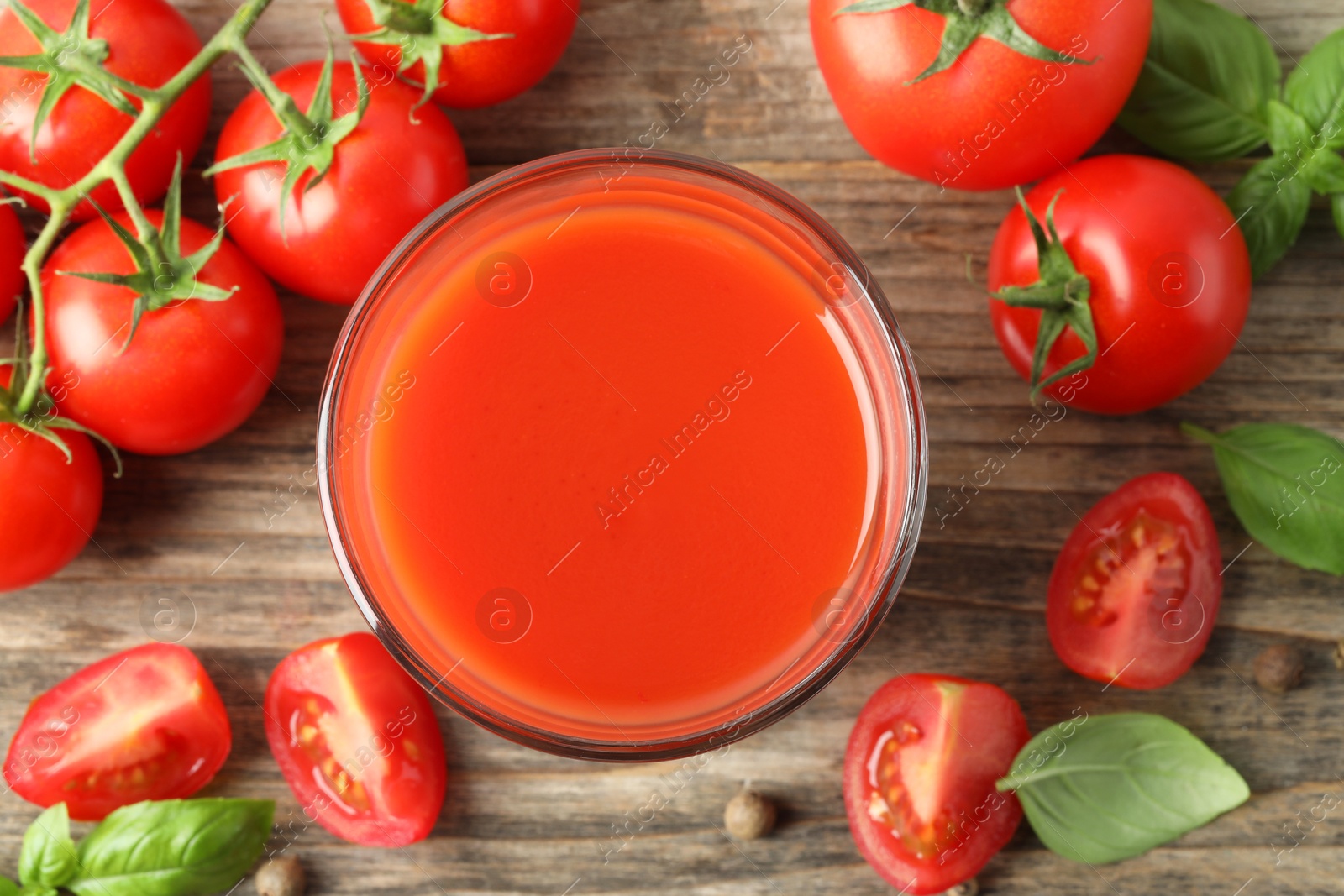 Photo of Tasty tomato juice in glass with fresh vegetables and spices on wooden table, flat lay