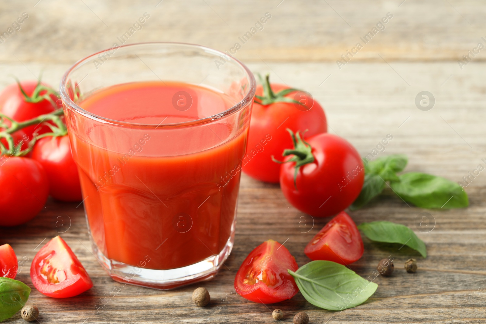 Photo of Tasty tomato juice in glass with fresh vegetables and spices on wooden table, closeup. Space for text