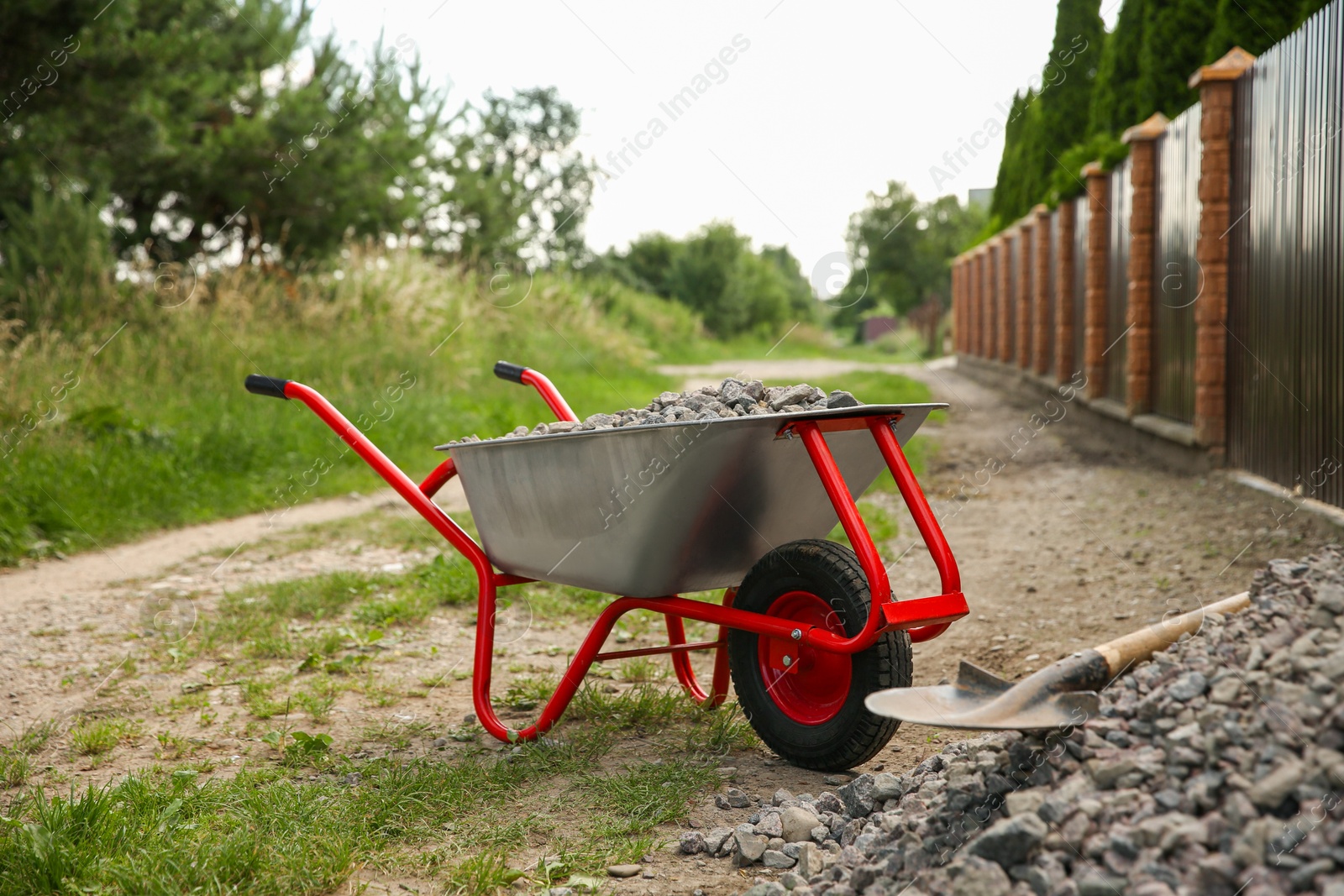 Photo of Wheelbarrow full of stones and shovel outdoors