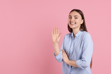 Photo of Happy woman waving on pink background, space for text