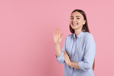 Happy woman waving on pink background, space for text