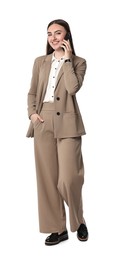 Beautiful woman in beige suit talking on smartphone against white background