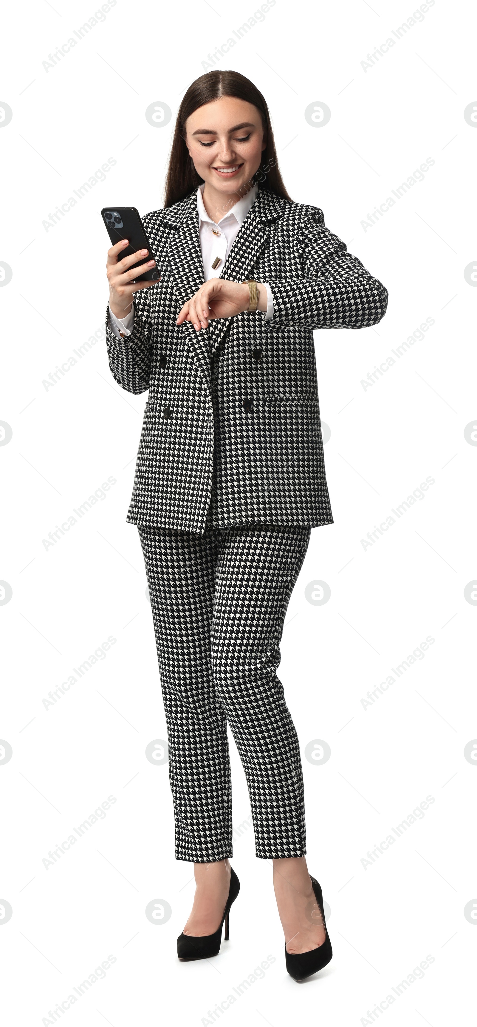 Photo of Beautiful woman in stylish suit with smartphone looking at wristwatch on white background