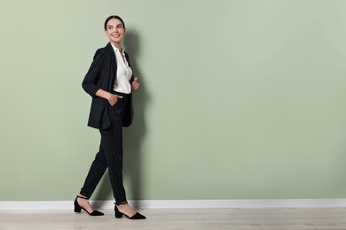 Beautiful woman in black striped suit indoors, space for text