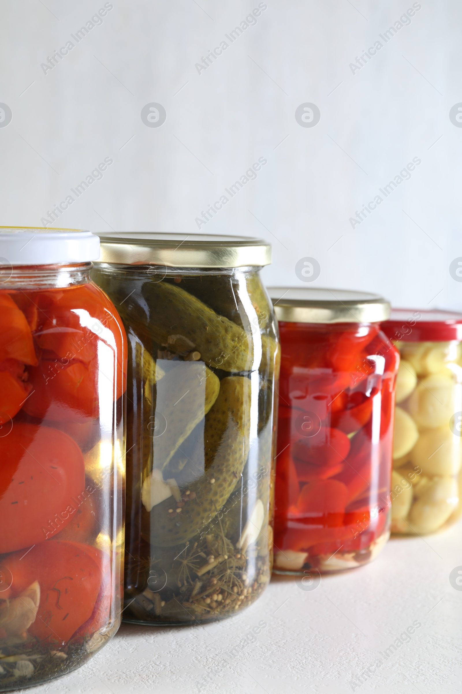 Photo of Tasty pickled vegetables and mushrooms in jars on white background, closeup