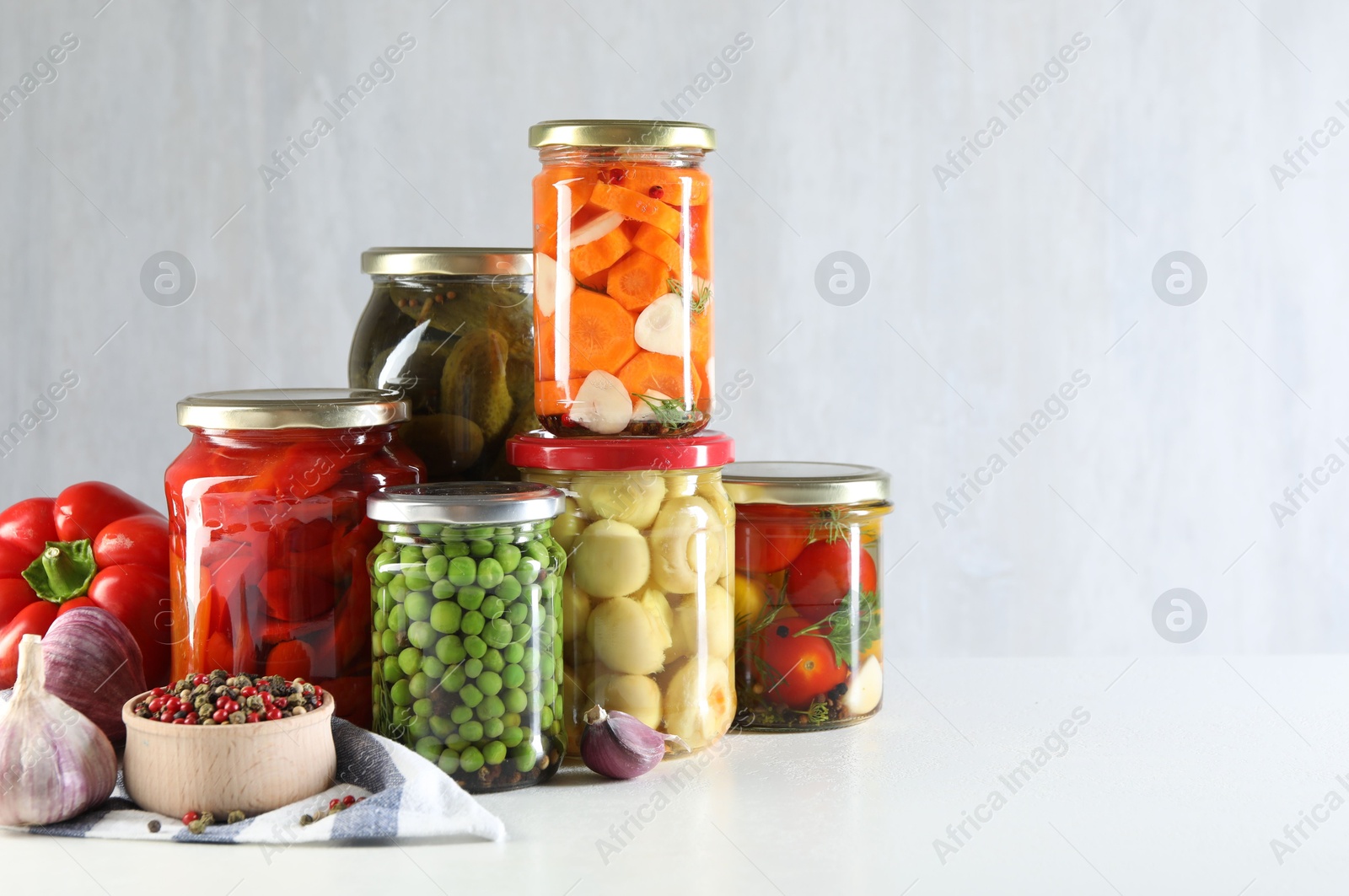 Photo of Jars with tasty pickled vegetables, mushrooms and spices on white background, space for text