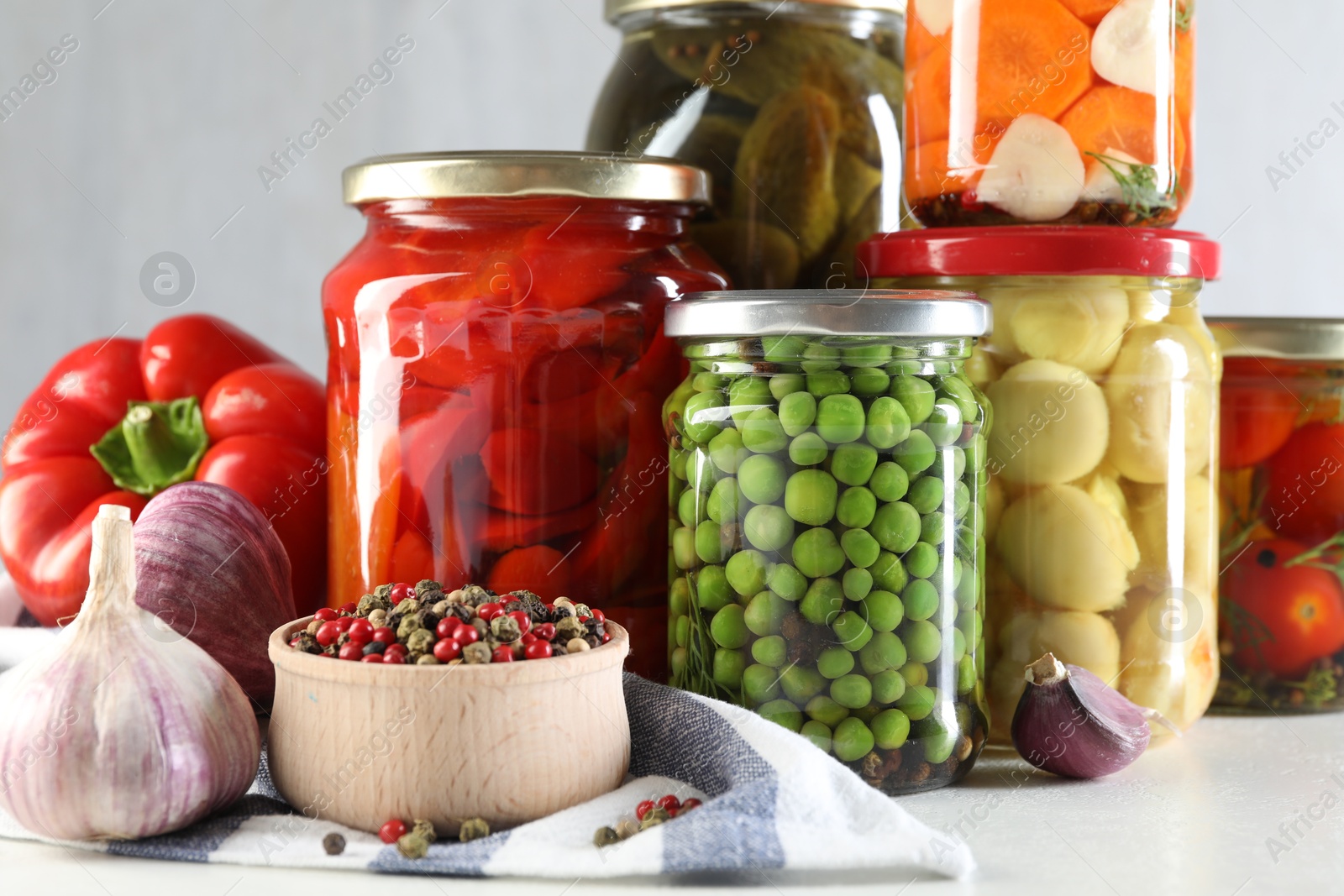 Photo of Jars with tasty pickled vegetables, mushrooms and spices on white background, closeup