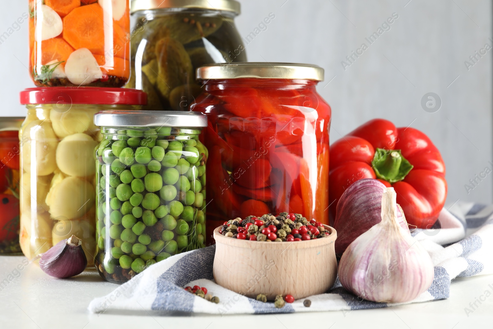 Photo of Jars with tasty pickled vegetables, mushrooms and spices on white background, closeup