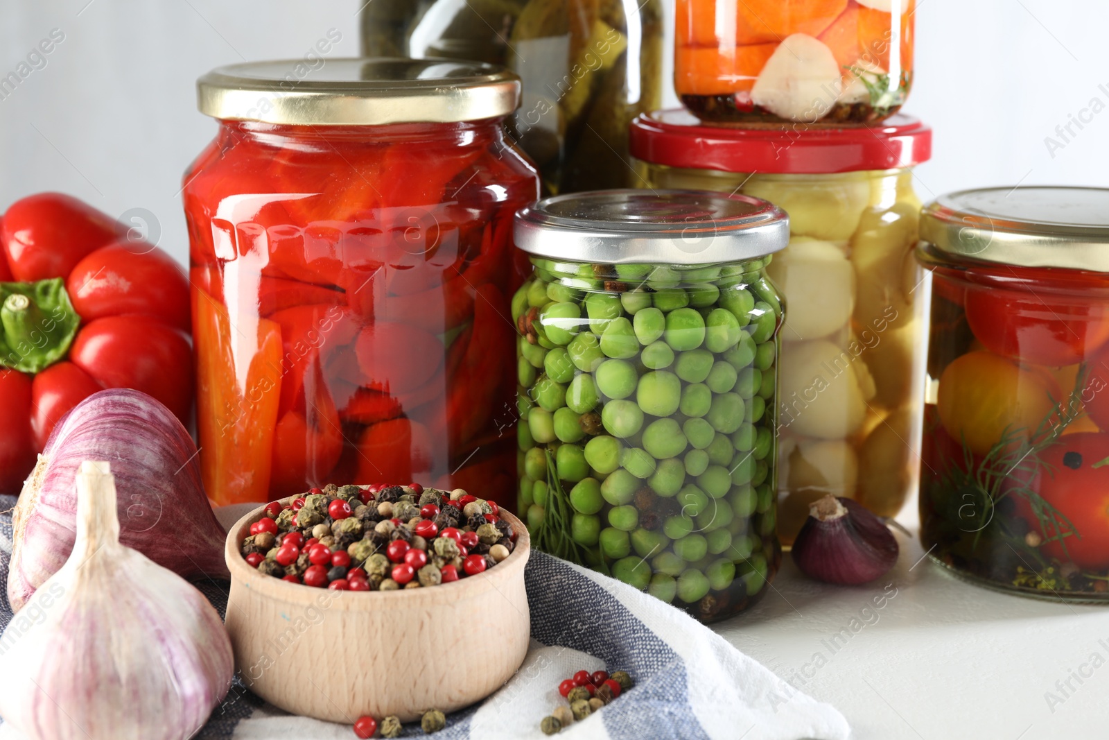 Photo of Jars with tasty pickled vegetables, mushrooms and spices on white background, closeup