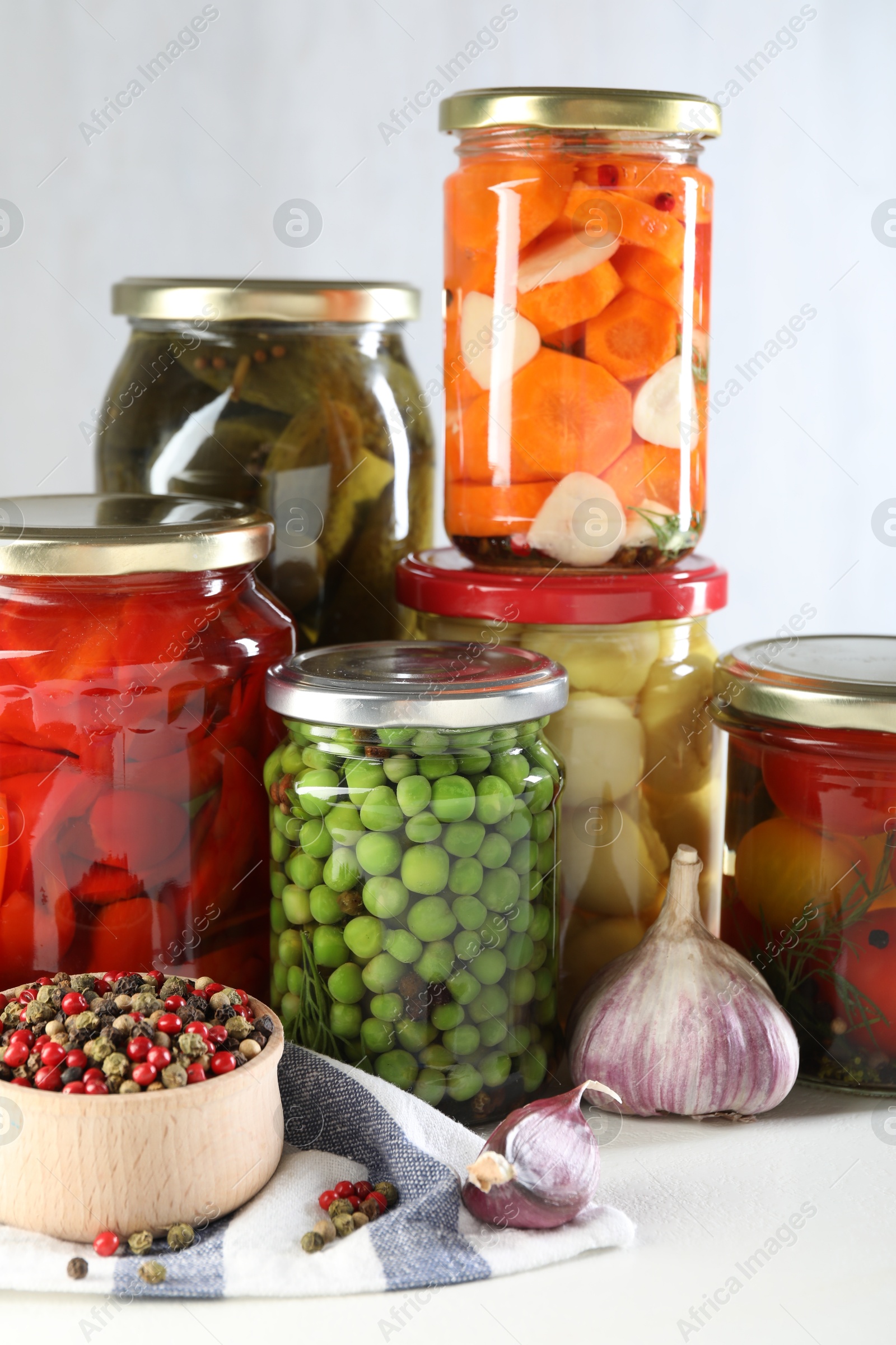 Photo of Jars with tasty pickled vegetables, mushrooms and spices on white background