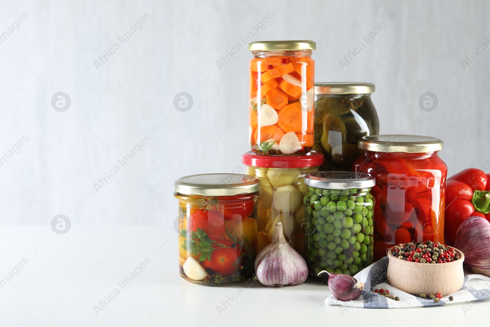 Photo of Jars with tasty pickled vegetables, mushrooms and spices on white background, space for text