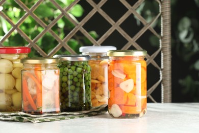 Photo of Tasty pickled vegetables and mushrooms in jars on white background