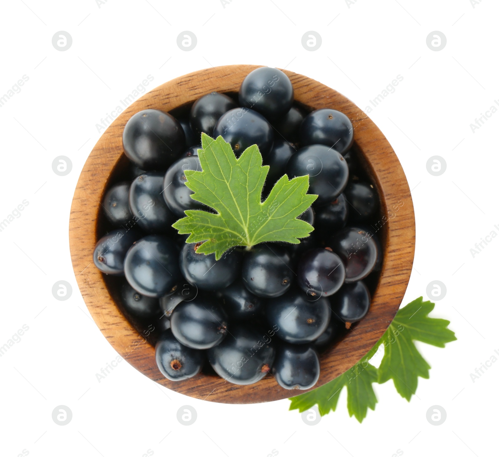 Photo of Bowl of ripe blackcurrants and green leaves isolated on white, top view