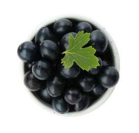 Photo of Bowl of ripe blackcurrants and green leaf isolated on white, top view