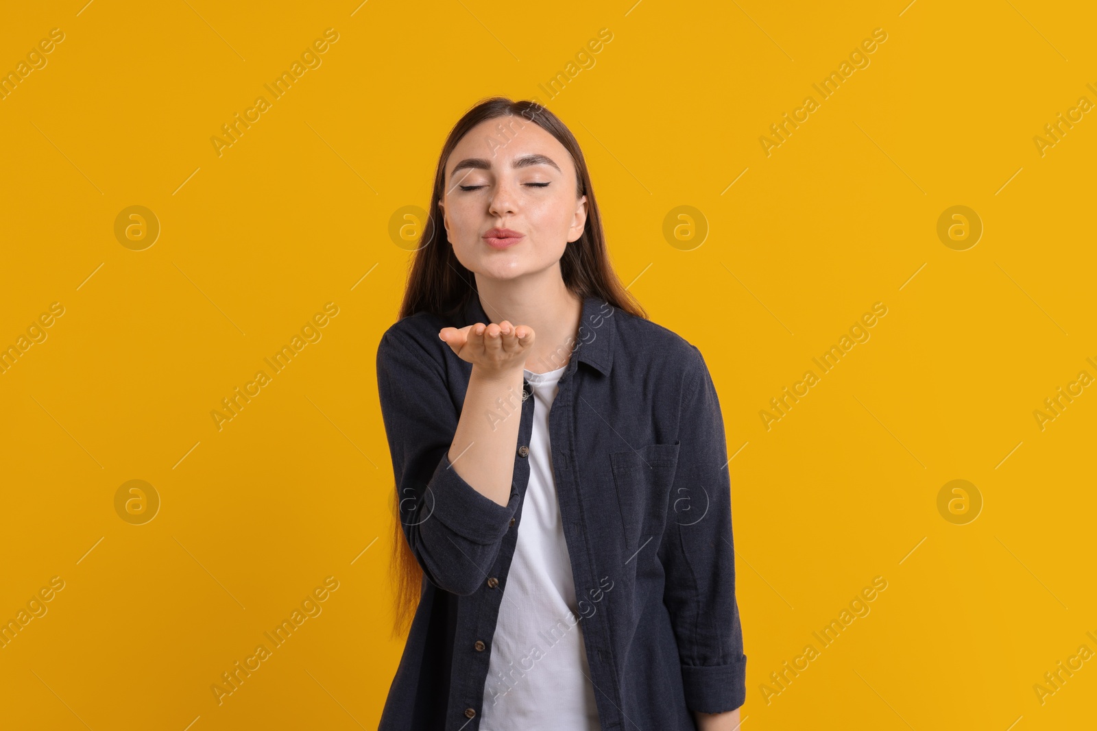 Photo of Beautiful woman blowing kiss on orange background