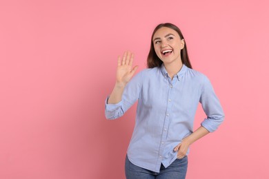 Happy woman waving on pink background, space for text