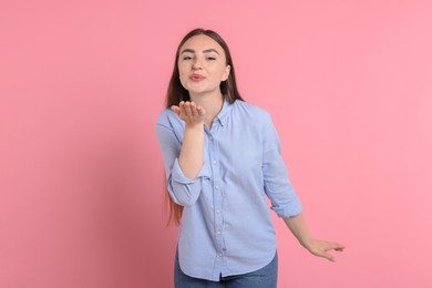 Photo of Beautiful woman blowing kiss on pink background