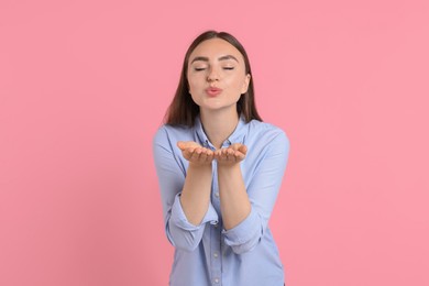 Photo of Beautiful woman blowing kiss on pink background