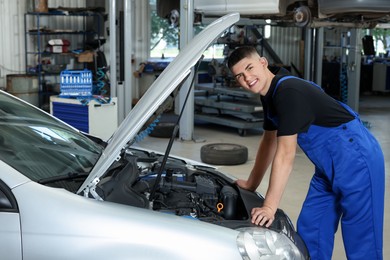 Young auto mechanic fixing car at automobile repair shop