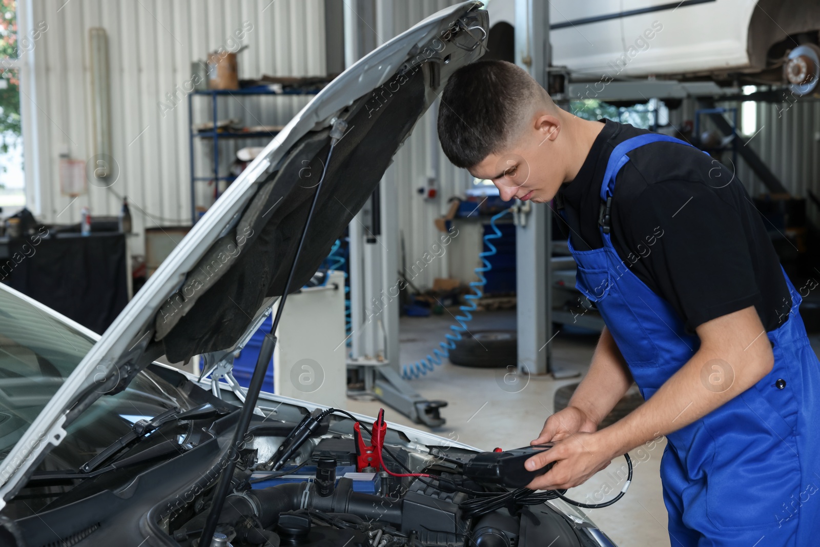 Photo of Young auto mechanic fixing car at automobile repair shop