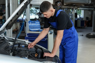 Young auto mechanic fixing car at automobile repair shop