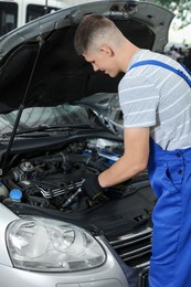 Photo of Young auto mechanic fixing car at automobile repair shop