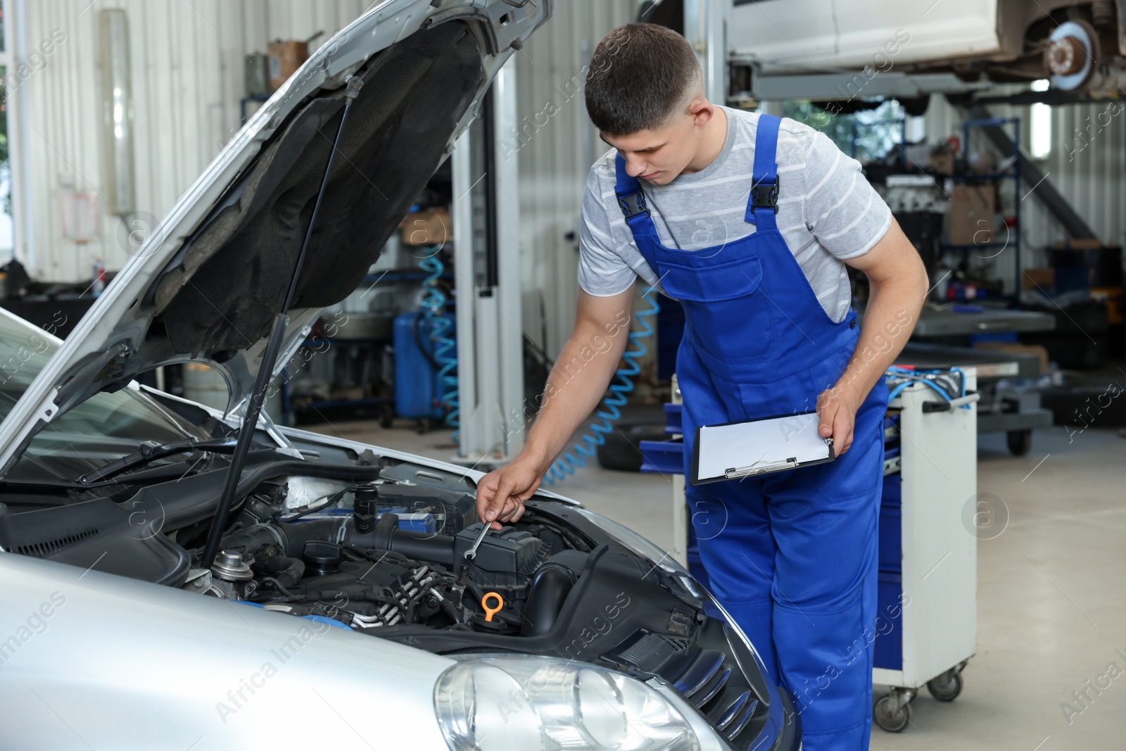 Photo of Young auto mechanic taking notes while doing car diagnostic at automobile repair shop