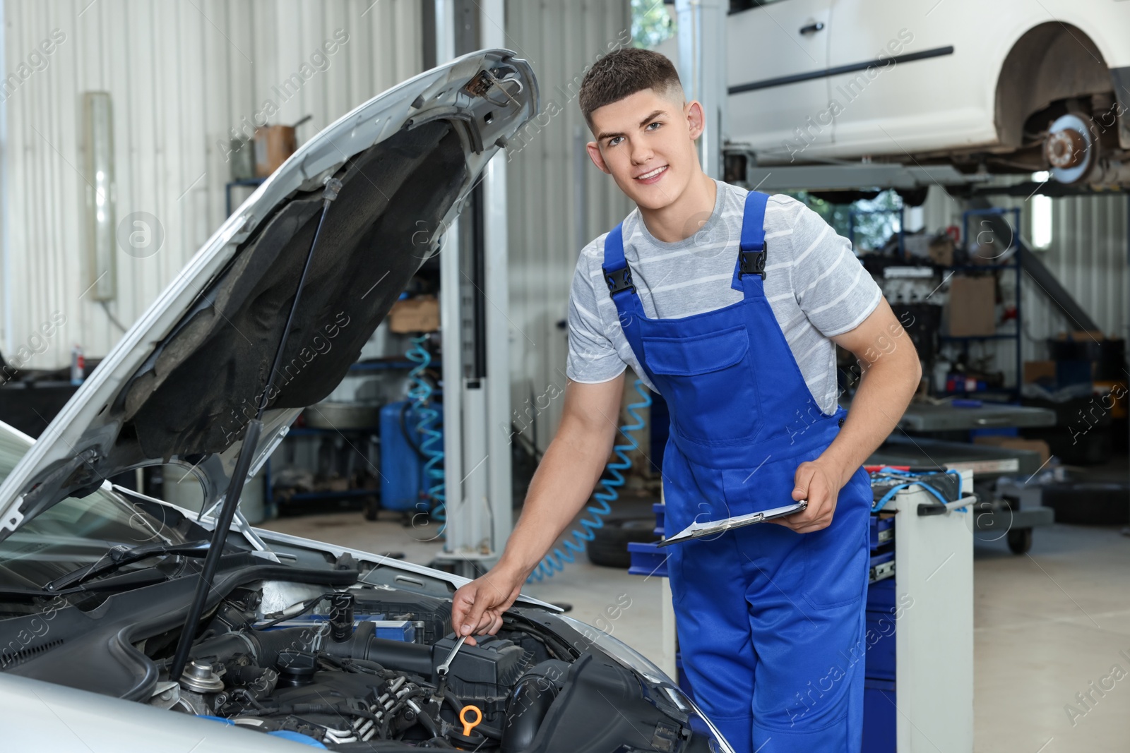 Photo of Young auto mechanic taking notes while doing car diagnostic at automobile repair shop