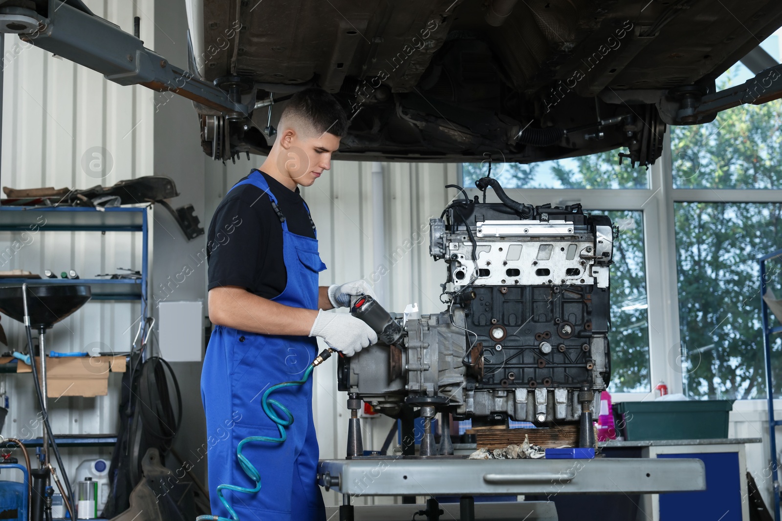 Photo of Young auto mechanic fixing motor at automobile repair shop. Car diagnostic