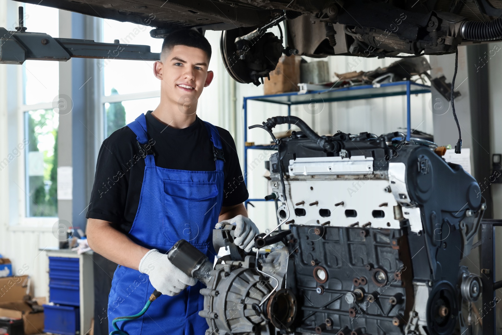 Photo of Young auto mechanic fixing motor at automobile repair shop. Car diagnostic