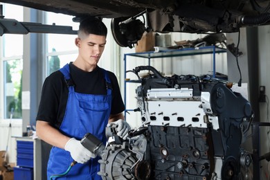 Young auto mechanic fixing motor at automobile repair shop. Car diagnostic