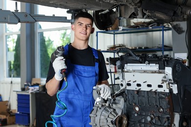 Photo of Young auto mechanic fixing motor at automobile repair shop. Car diagnostic