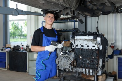 Photo of Young auto mechanic fixing motor at automobile repair shop. Car diagnostic