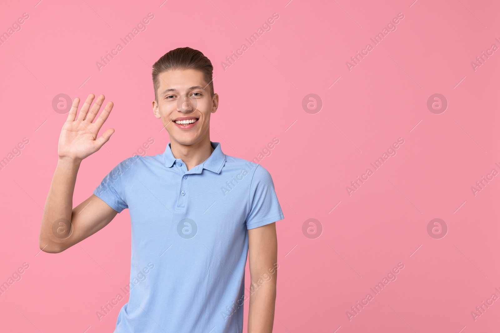 Photo of Goodbye gesture. Happy young man waving on pink background, space for text