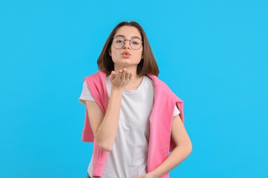 Photo of Beautiful teenage girl blowing kiss on light blue background