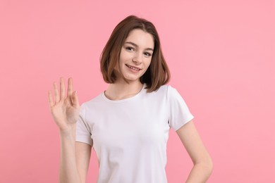 Photo of Happy teenage girl waving on pink background