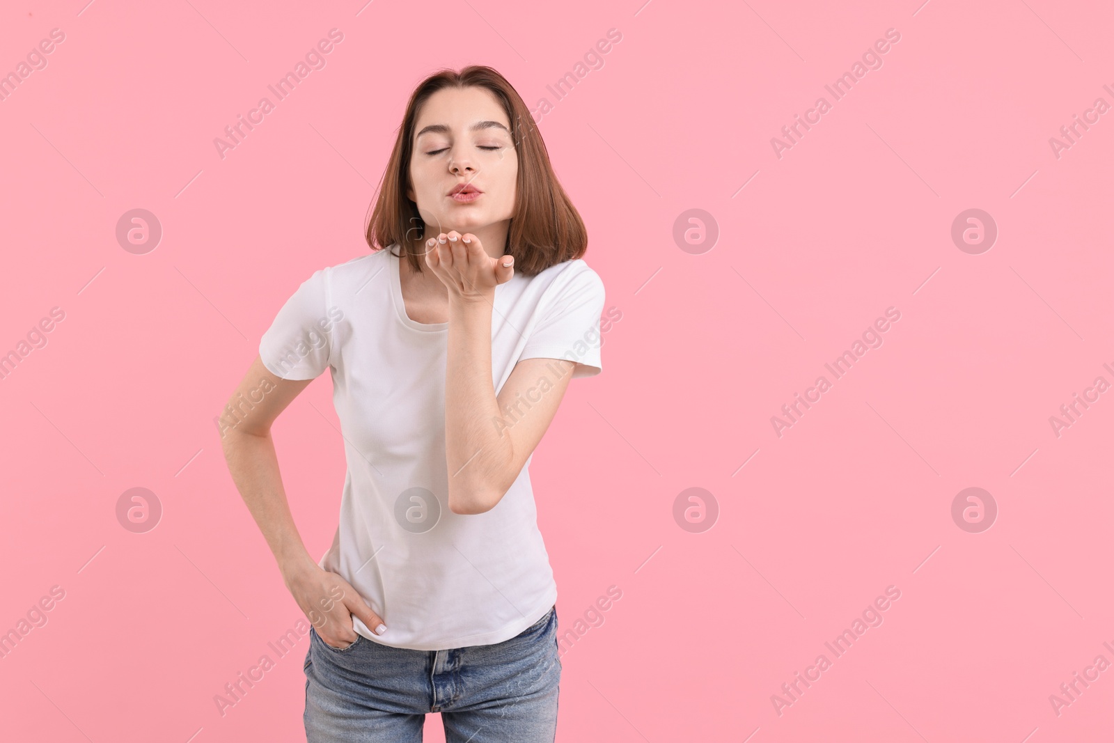 Photo of Beautiful teenage girl blowing kiss on pink background, space for text