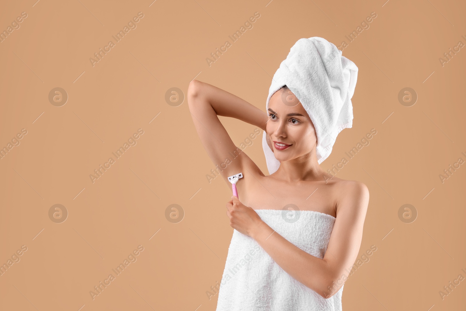 Photo of Smiling woman shaving armpit on beige background. Space for text