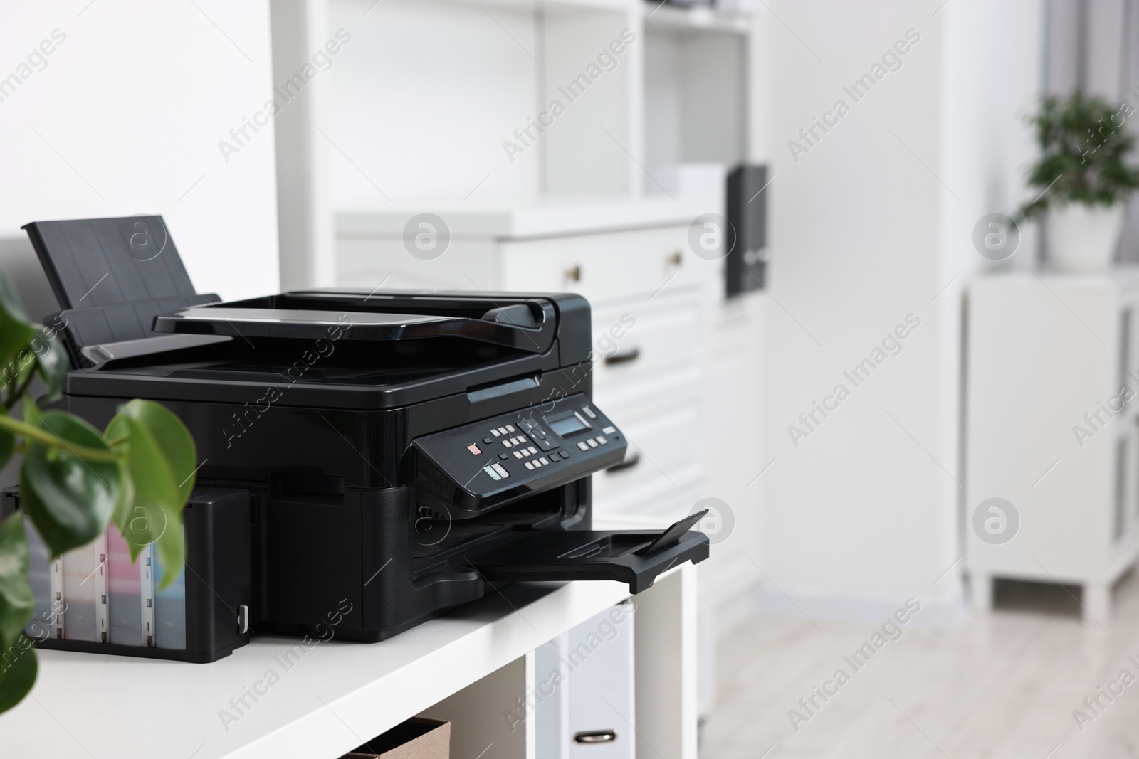 Photo of Modern printer on white table in office. Space for text