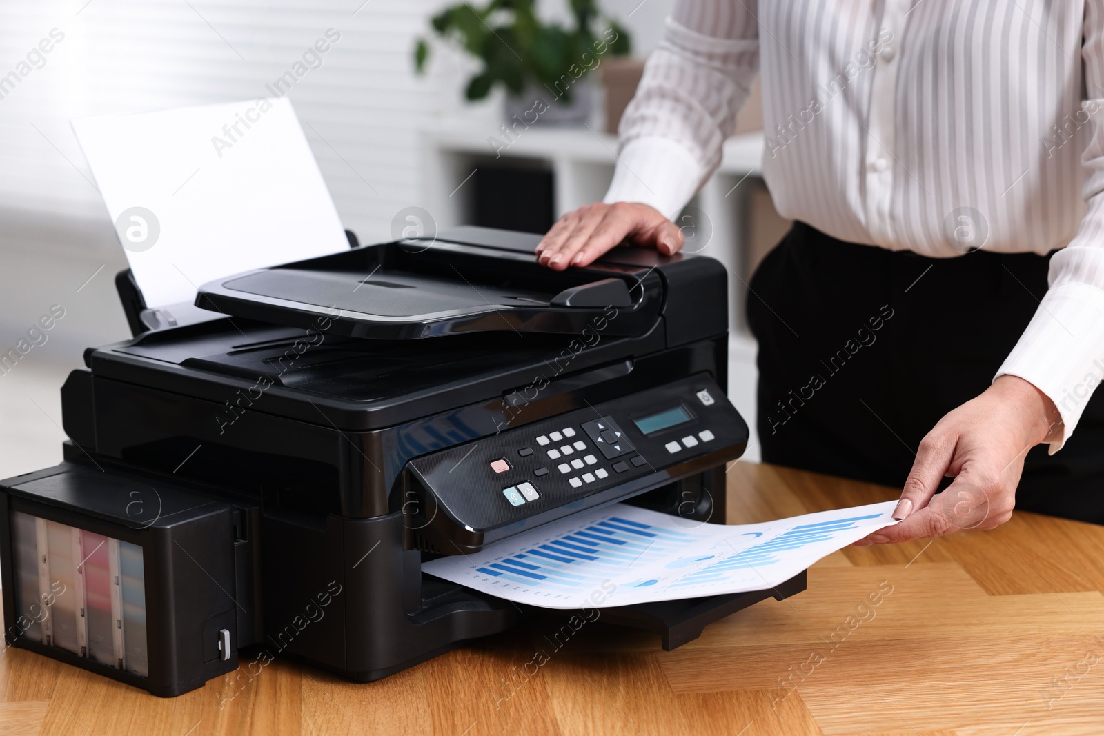 Photo of Woman using modern printer at workplace indoors, closeup