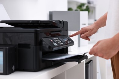 Photo of Woman using modern printer at workplace indoors, closeup