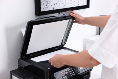 Photo of Woman using modern printer at workplace indoors, closeup