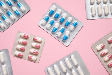 Antibiotic pills in blisters on pink background, flat lay