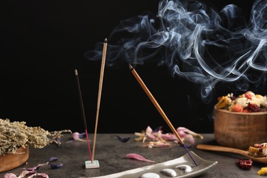 Photo of Aromatic incense sticks smoldering on grey table